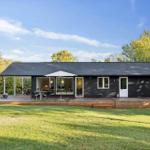 Black house with terrace, garden, and seating areas outdoors.