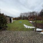 Backyard with lawn, shed, and small house. Snow lies in some places.