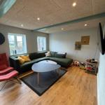 Living room with green sofa, round table, and wooden floor.