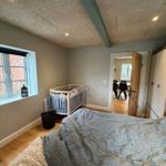 Bedroom with crib, bed, and window. Hallway to the kitchen.