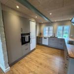 Modern kitchen with wooden floor, white cabinets, and built-in oven.