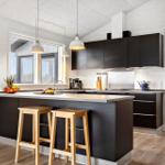 Moderne Küche mit dunklen Schränken, Kücheninsel und Holzstühlen.