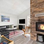 Wohnzimmer mit Kamin, Sofa, Fernseher und Holzboden.