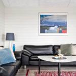 Ein Wohnzimmer mit schwarzen Ledersofas, einem runden Tisch und Wandbildern.