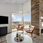 Wohnzimmer mit Kamin, TV und Blick auf Dünen.