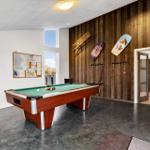 Billardtisch mit grünem Tuch und Kugeln in einem Raum mit Holzwand und Fenster.