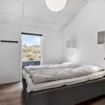 Schlafzimmer mit Bett, TV und Fensterblick auf Dünen.