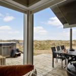 Terrasse mit Sitzgelegenheit, Esstisch und Whirlpool. Blick auf Dünen und Meer.