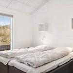 Schlafzimmer mit Doppelbett und Fensterblick auf Dünen.