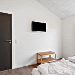 Schlafzimmer mit Bett, TV und Fensterblick auf Dünen.