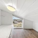 Zimmer mit Bett, Fenster und Holzboden. Blick auf die Landschaft.