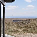 Blick vom Haus aus auf Strand und Meer mit Dünen im Vordergrund.
