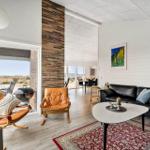 Wohnzimmer mit Ledersofa, zwei braunen Ledersessel und rotem Teppich.