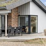 Haus mit Holzterrasse, Sitzgruppe und Glasfront zur Aussicht.