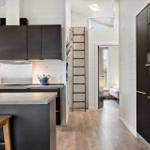 Küche mit dunklen Schränken, Edelstahlgeräten und Holzboden. Treppe führt zum Dachboden.