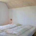 Zimmer mit Doppelbett, Holzdecke und Fenster. Beide Betten sind mit weißen Bettwäschen bezogen.