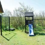 Hinter dem Haus befindet sich ein Spielplatz mit Rutsche und Schaukel.