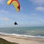 Paraglider fliegt über Strand und Meer.