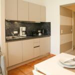 Küche mit Arbeitsplatte, Spüle und Küchengeräten. Tisch mit Geschirr und Stühlen.