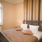 Schlafzimmer mit Bett, Fenster und gestreifter Wandverkleidung.