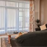 Wohnzimmer mit Sofa, Fernseher und großem Fenster