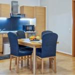 Küche mit Esstisch und vier Stühlen. Hintergrund: Holzschrank, Dunstabzug, Mikrowelle.