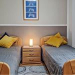 Zwei Einzelbetten mit gelben Kissen und Nachttisch dazwischen.