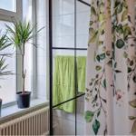 Badezimmer mit Fenster, Pflanzen und Duschvorhang mit Blumenmuster.