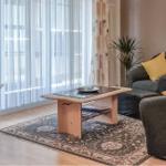 Wohnzimmer mit Sofa, Couchtisch und Fernseher vor Fenster mit Vorhängen.