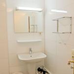 Badezimmer mit Waschbecken, Spiegel und Handtuchhalter.