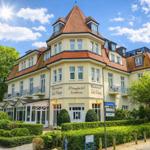 Strandhotel Sonnenburg mit Café Melange und rotem Ziegeldach unter blauem Himmel.