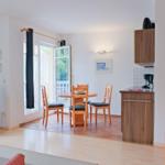 Wohnküchenbereich mit Essplatz, TV und Blick auf Balkon.