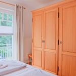 Schlafzimmer mit Holzschrank, Fenster und Bett
