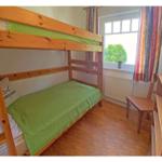 Ein Schlafzimmer mit einem Holzbett und einem Fenster mit Vorhängen.