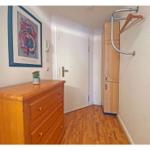 Flur mit Holzschrank, Kleiderständer und Schminktisch mit Bild an der Wand.