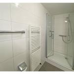 Badezimmer mit Dusche, Heizkörper und Handtuchhalter.