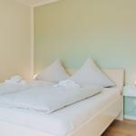 Schlafzimmer mit Doppelbett, weißen Bettwäsche und Nachttisch mit Lampe.