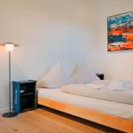 Ein Schlafzimmer mit Holzbett, blauer Gardine und Wandbild.