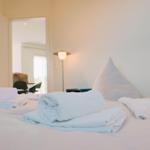 Ein Bett mit gefalteten Handtüchern und Kissen. Im Hintergrund ist ein Lampenlicht sichtbar.