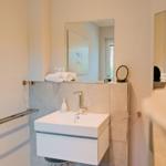 Badezimmer mit Waschbecken, Spiegel und Handtuchhalter.