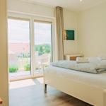 Schlafzimmer mit Bett, Balkon und Blick auf Garten