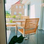 Terrasse mit Holztisch und Stühlen, Blick auf ein Haus und Garten.