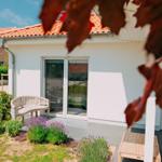Wohnung mit Terrasse, Sitzgelegenheiten und Blumenbeeten im Vorgarten.