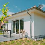 Moderne Villa mit Terrasse, Sitzgelegenheit und Satellitenanlage.