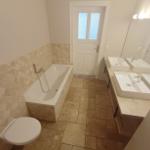 Bad mit Badewanne, Doppelwaschbecken und Toilette.