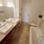 Badezimmer mit Dusche, Badewanne, zwei Waschbecken und Toilette.