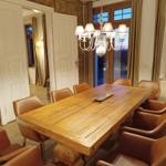 Esszimmer mit massivem Holztisch und Ledersitzen unter Kronleuchter.