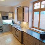 Küche mit Holzschränken, Arbeitsplatte und Fensterblick auf Backsteinmauer