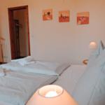 Schlafzimmer mit Bett, Kissen, Lampen und Wandbildern.
