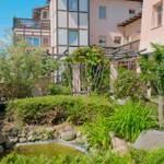 Garten mit Teich, Sträuchern und Pergola vor mehrstöckigem Haus